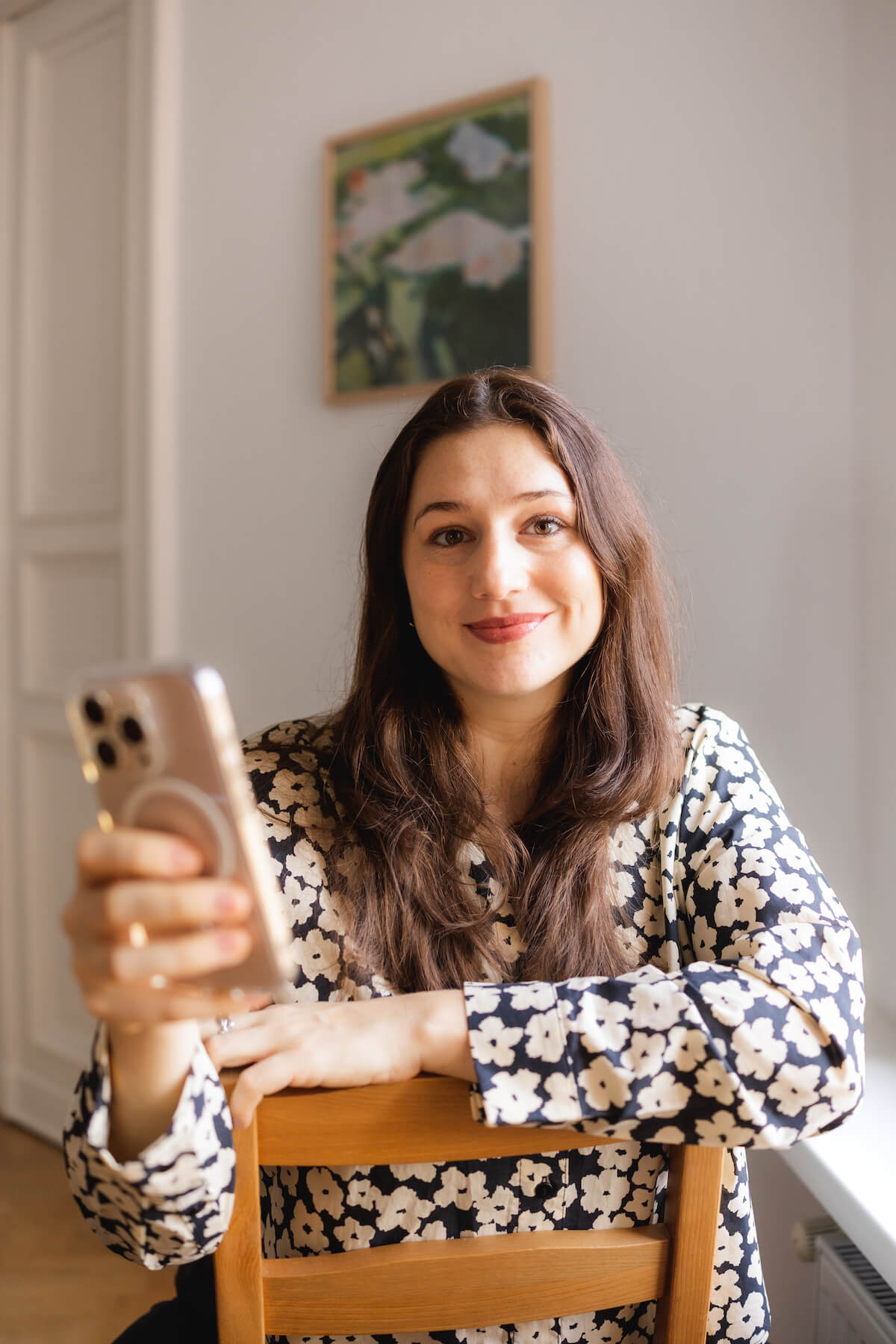 Alisa Fries sitzt verkehrt herum auf einem Stuhl und hält ein Handy in der Hand