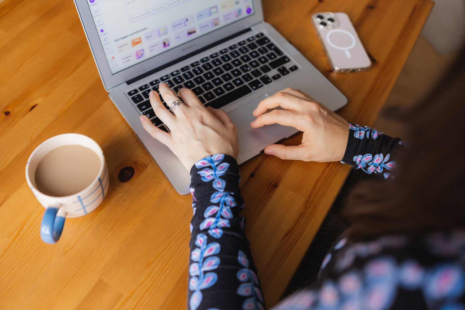 seitliche Sicht auf einen Laptop an dem jemand sitzt und arbeitet